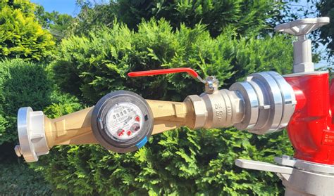 strażacy OSP podłączający wąż do hydrantu z widocznym wodomierzem
