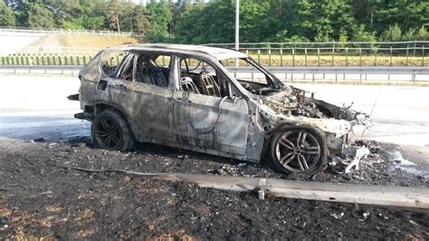 Spalone BMW na parkingu miejskim, otoczone taśmą policyjną
