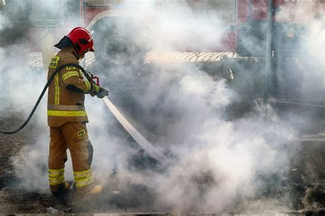 Zdjęcie hali lakierni objętej pożarem, strażaków w akcji z podnośnikiem