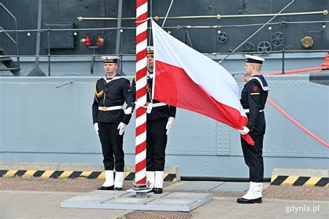 Tematyczne zdjęcie flagi OSP powiewającej na maszcie przed remizą
