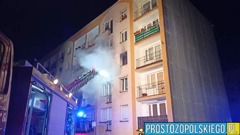 Zdjęcie strażaków gaszących pożar mieszkania w bloku