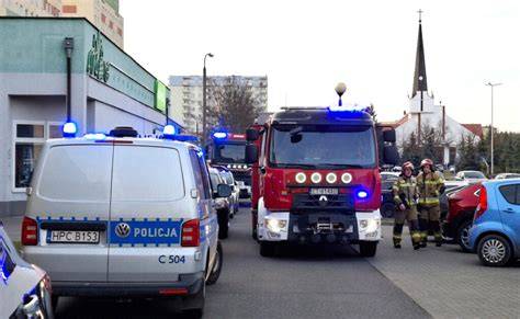 Zdjęcie przedstawiające służby ratunkowe (straż pożarna, karetki, policja) na tle górskiego kurortu narciarskiego w nocy.