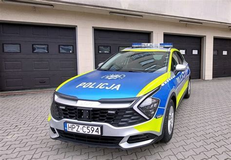 radiowóz policyjny pod drzewem z kotem i dzieckiem