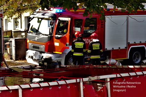 Wóz strażacki i strażacy rozwijający węże pożarnicze Bezalin w akcji gaśniczej