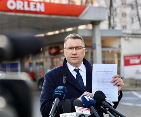 Politycy podczas konferencji prasowej przed stacją paliw Orlen w Kielcach, mikrofony i logo partii