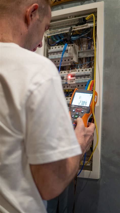 Zdjęcie przedstawiające technika wykonującego pomiary elektryczne w rozdzielnicy