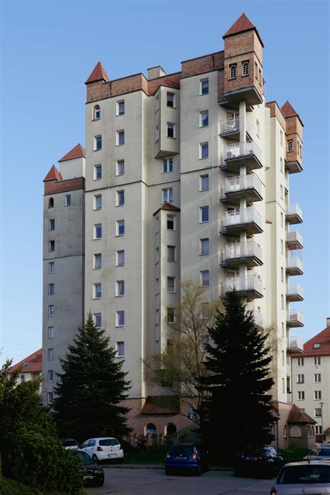 zdjęcie przedstawiające blok mieszkalny w Krakowie z widocznymi śladami pożaru na szóstym piętrze, z rozstawionym skokochronem strażackim pod oknem