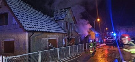 zdjęcie z akcji gaśniczej domu w nocy, z widocznym dymem i światłami straży pożarnej