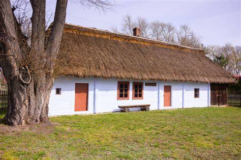 historyczne zdjęcie drewnianych domów krytych strzechą oraz wczesnej sikawki strażackiej