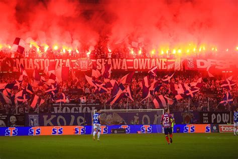 Zdjęcie przedstawiające gorącą atmosferę na stadionie podczas zawodów strażackich, kibice i zawodnicy