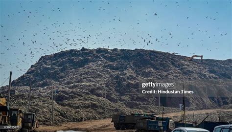 Photo of the Ghazipur landfill in India, showing its immense size and smoke plumes