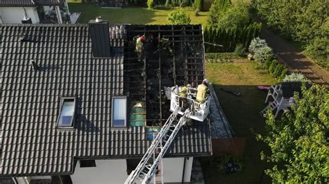 Strażacy gaszący pożar dachu domu jednorodzinnego po uderzeniu pioruna
