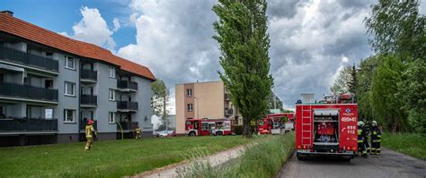 Strażacy prowadzący ewakuację i akcję gaśniczą w budynku wielorodzinnym