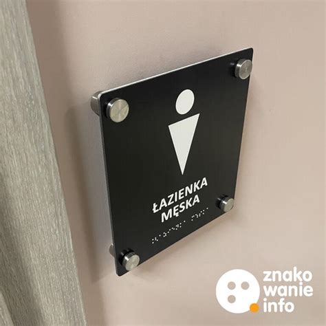 Zbliżenie na tabliczkę informacyjną WC z wytłoczonym alfabetem Braille’a