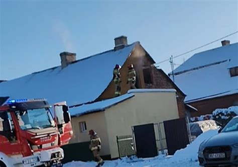 Strażacy gaszący pożar domu jednorodzinnego w Gostyniu, dym wydobywający się z dachu