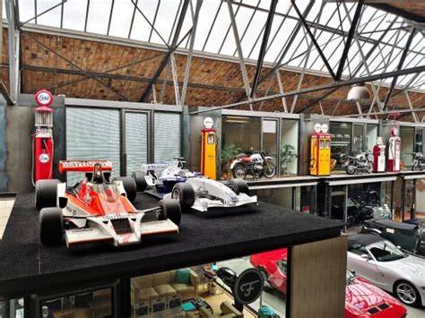 Wnętrze hali Classic Remise, pokazujące różnorodność klasycznych samochodów i industrialne elementy architektoniczne