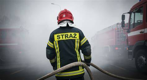 Strażacy w akcji gaśniczej na dachu płonącego budynku wielorodzinnego w Bielkowie