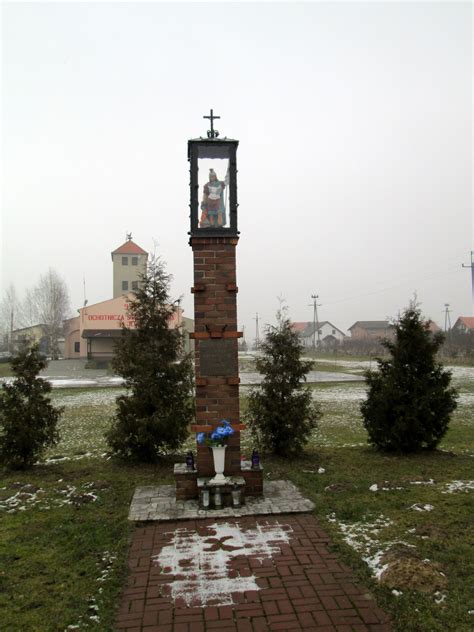 Zdjęcie przedstawiające Dom Strażaka w Chorągwicy z figurą św. Floriana przed budynkiem.