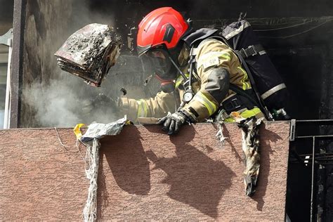 Zdjęcie przedstawiające strażaków pracujących na miejscu pożaru w wieżowcu