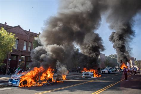 Thematic photo of a burning building with smoke and a police car in the foreground