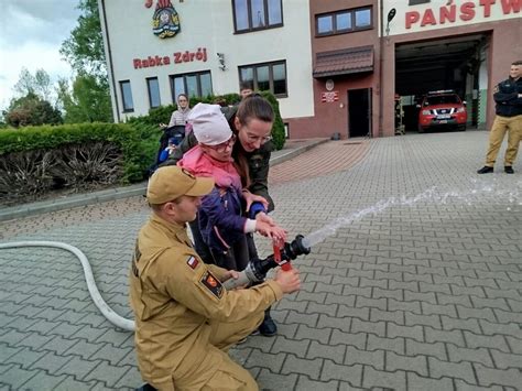 Dzieci uczestniczące w pokazie lania wody z węża strażackiego.