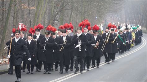 Zdjęcie przedstawiające przemarsz strażaków ulicami Goleniowa podczas deszczu, z orkiestrą i pocztami sztandarowymi.