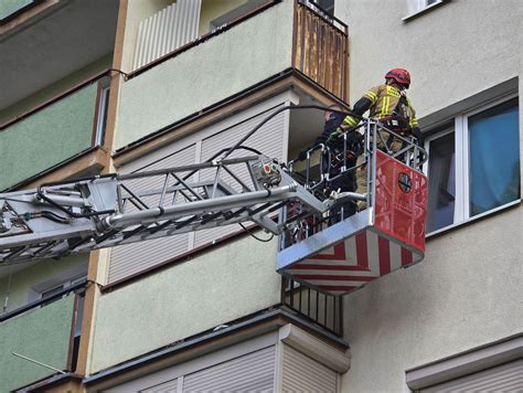 Strażacy gaszący płonący budynek z użyciem drabiny mechanicznej.