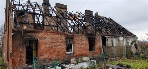 Zdjęcie kamienicy z widocznymi zniszczeniami po pożarze na poddaszu, strażacy na miejscu