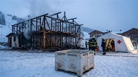 The aftermath of a bar fire in a Swiss ski resort, showing emergency services and structural damage.