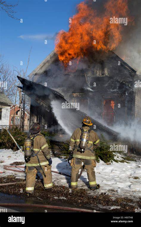 Photo of firefighters extinguishing a house fire, focus on attic area