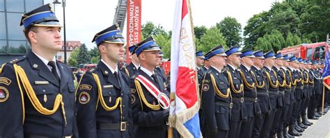 Zdjęcie strażaków w pełnym umundurowaniu galowym podczas oficjalnej uroczystości.