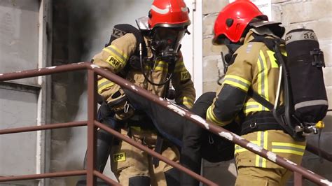 strażacy ewakuujący ludzi z zadymionego budynku
