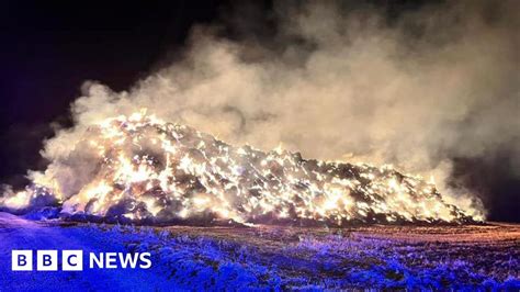 Thematic photo of firefighters extinguishing a large haystack fire at night.