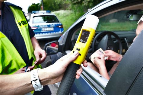 Zdjęcie przedstawiające kierowcę dmuchającego w policyjny alkomat