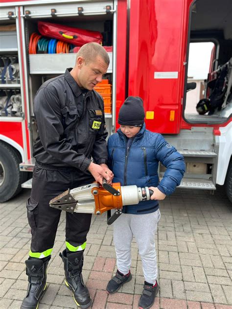 Zdjęcie strażaka wręczającego maskotkę przestraszonemu dziecku po wypadku