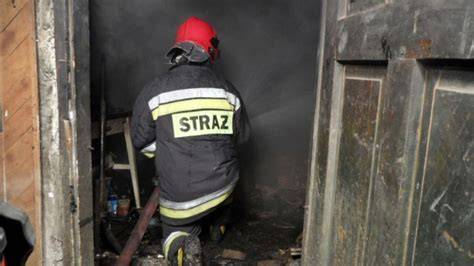 strażacy gaszący pożar w garażu i kotłowni budynku mieszkalnego, dym, akcja ratownicza nocą