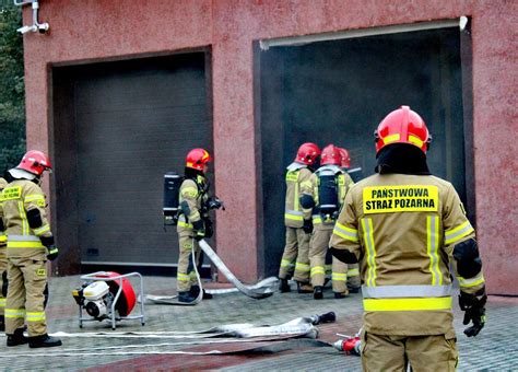 Ilustracja przedstawiająca akcję gaśniczą straży pożarnej w terenie zabudowanym