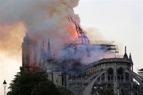 Zdjęcie płonącej katedry Notre-Dame z widocznym dymem wydobywającym się z okolic iglicy.