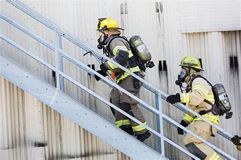 Photo of firefighters in full protective gear and oxygen tanks climbing stairs