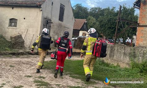 Zdjęcie dokumentujące akcję gaśniczą w gospodarstwie rolnym, przedstawiające strażaków w trakcie działań przy budynku gospodarczym.