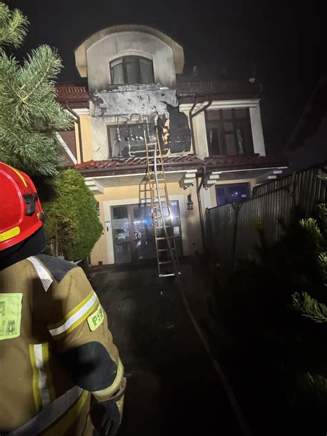 Zdjęcie przedstawiające działania straży pożarnej podczas pożaru altanki i elewacji budynku mieszkalnego.