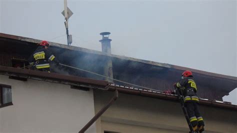 Strażacy gaszący pożar poddasza budynku mieszkalnego