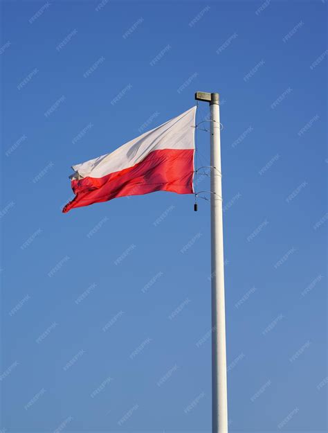 Tematyczne zdjęcie: Flaga ZOSP RP dumnie powiewająca na maszcie przed remizą OSP