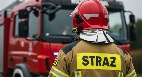 Tematyczne zdjęcie przedstawiające nowy wóz ratowniczo-gaśniczy OSP KSRG Lubicz na tle remizy, z widocznymi strażakami i gośćmi