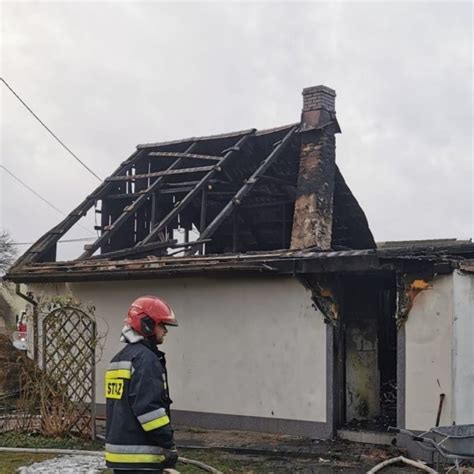 strażacy usuwający zniszczone elementy dachu po pożarze domu