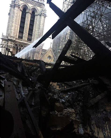 Widok na zniszczone wnętrze katedry Notre Dame po pożarze, z widocznymi ocalałymi sklepieniami