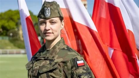 Dziewczyna w mundurze strażackim trzymająca prądownicę i celująca strumieniem wody, widoczne zaangażowanie i radość