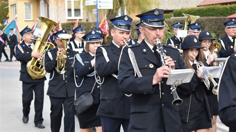 Grupa strażaków i członków orkiestry dętej podczas uroczystości jubileuszowej na placu w Bobrownikach.