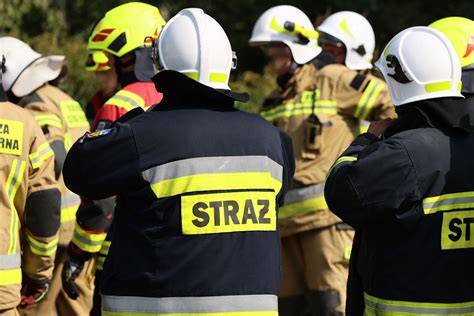 Strażak ochotnik w umundurowaniu, wsiadający do prywatnego samochodu z kluczykami w ręku