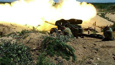 armata przeciwpancerna MT-12 Rapira w akcji, strzelająca w kierunku płonącego szybu